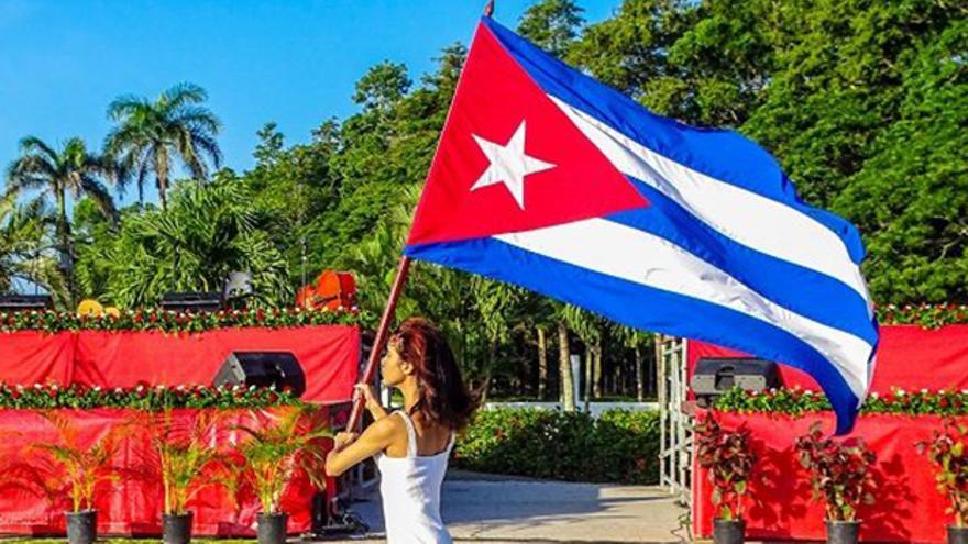 Una mujer ondea una bandera de Cuba en un acto conmemorativo a José Martí en Granma. (Cubadebate)