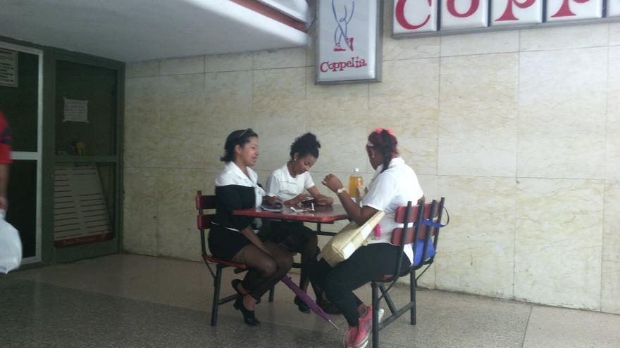 Las empleadas de la heladería Coppelia, en la ciudad de Camagüey, almuerzan tranquilas a las afueras del local, que no recibe suministro del producto desde que se paralizó la industria. (14ymedio)