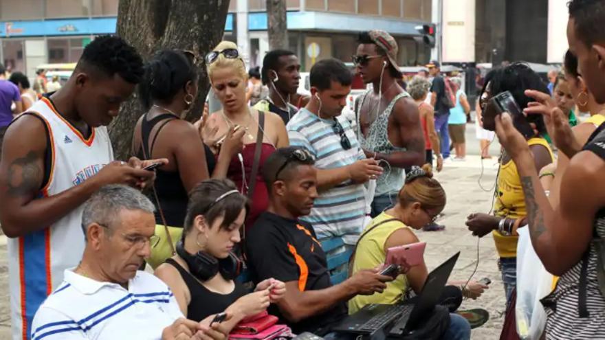 Cubanos usando una red de wifi en una zona pública. (EFE)