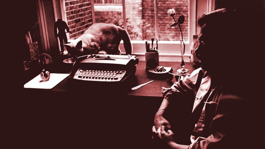 Guillermo Cabrera Infante, con su gato Offenbach y su máquina de escribir. Al fondo, el espadachín sin cabeza que el escritor trajo consigo desde La Habana. (Pinterest)