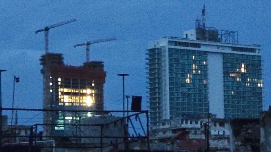 En pleno apagón, sobresalen las ventanas iluminadas del hotel Habana Libre y el despilfarro energético en la construcción de la Torre K, al amanecer de este miércoles. (14ymedio) 