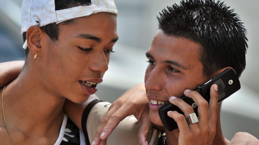 Jóvenes cubanos conversan telefónicamente a través de un celular. (EFE)