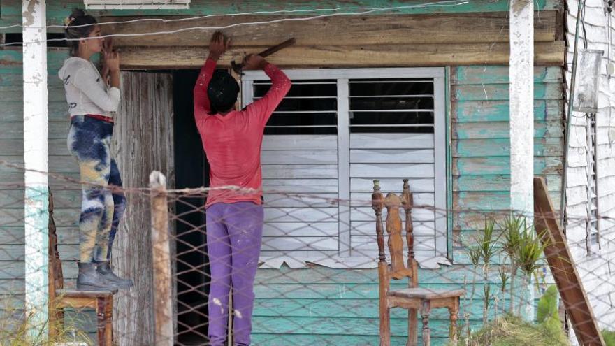 Dos mujeres intentan arreglar una vivienda en San Juan y Martínez después del paso de Ian. (EFE)