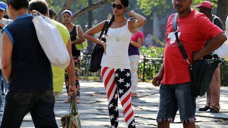 Una mujer ataviada con la bandera de Estados Unidos en La Habana mientras espera la guagua en el Parque de la Fraternidad. (EFE)
