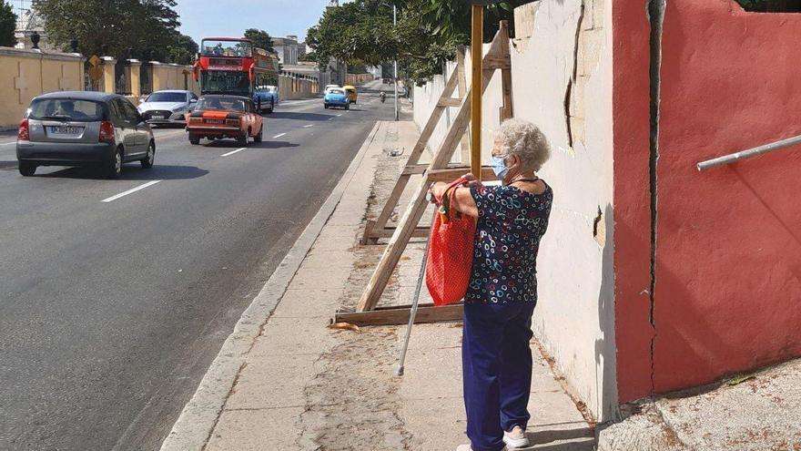 La acera deteriorada no daba muchas posibilidades a la mujer que terminó por resignarse a esperar porque el tráfico disminuyera para cruzar la calle. (14ymedio)