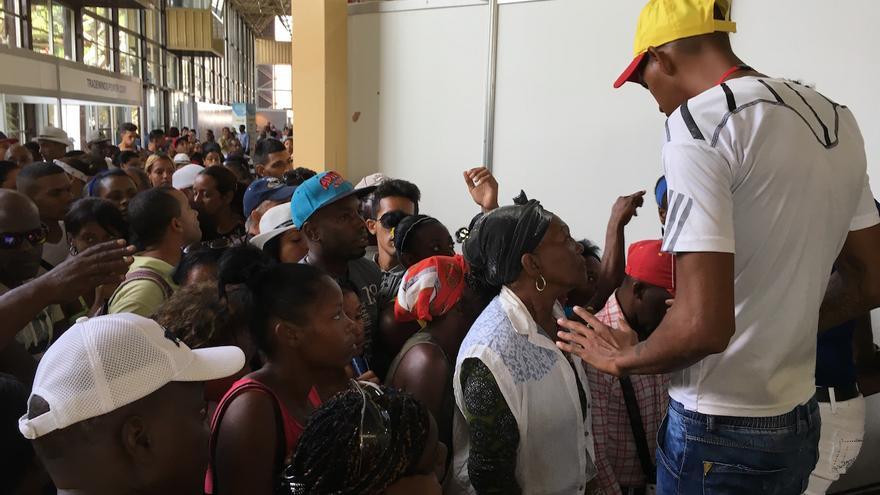 Un hombre trata de contener a la multitud que quiere pasar a la Feria de La Habana. (14ymedio)