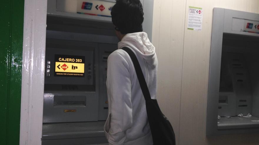 Un joven saca dinero en un cajero automático cubano