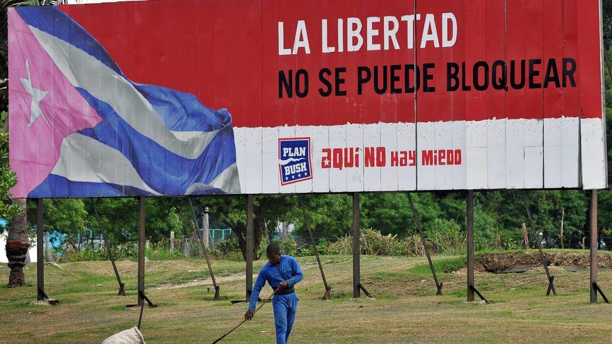 Un trabajador barre frente a un anuncio propagandístico en La Habana. (EFE)