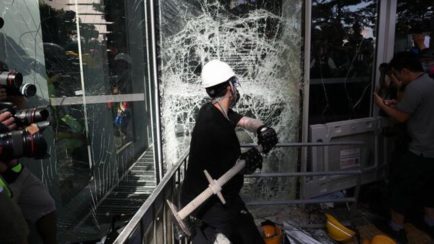   Un manifestante rompe una cristalera del Consejo Legislativo en Hong Kong (China) este lunes. (Ritchie B. Tongo / EFE)