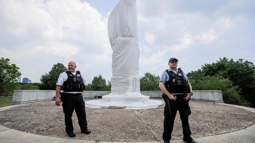 Dos policías mientras custodian una estatua desfigurada de Cristóbal Colón durante una manifestación en Chicago, Illinois (EE UU), en junio de 2020. (EFE/EPA/Tannen Maury)