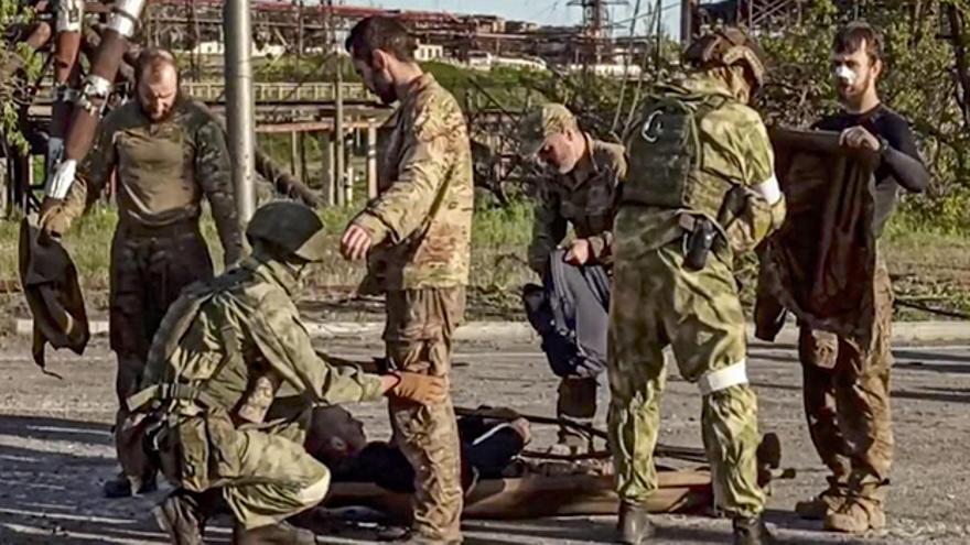  Imagen tomada de un video facilitado por el ministerio de Defesa ruso que muestra a varios soldados rusos revisando a militares ucranianos, al salir de la acería de Azovstal, en Mariúpol. (EFE).