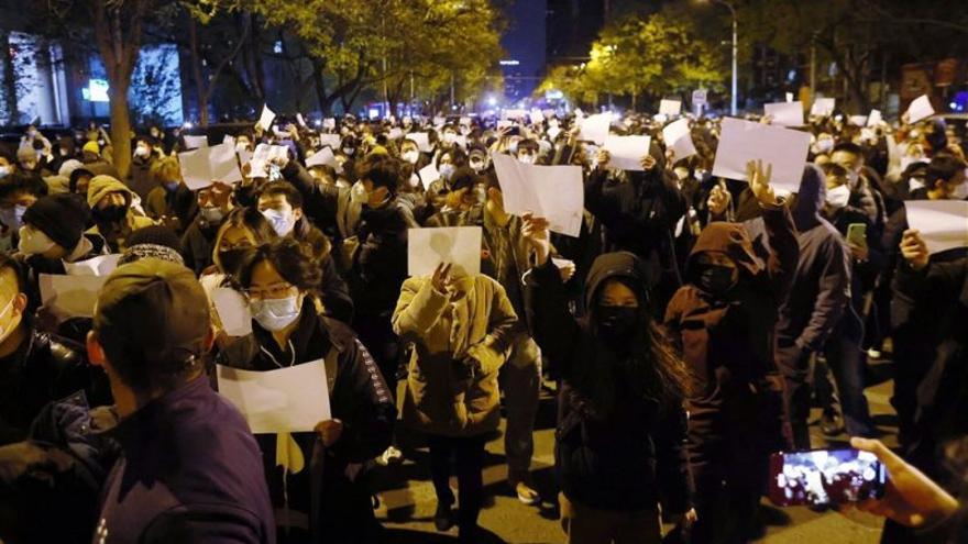 Manifestantes agitan papeles blancos en una protesta en Pekín contra la política "cero covid" tras un incendio en Urumqi que mató a 10 personas. (EFE/EPA/Mark R. Cristino)