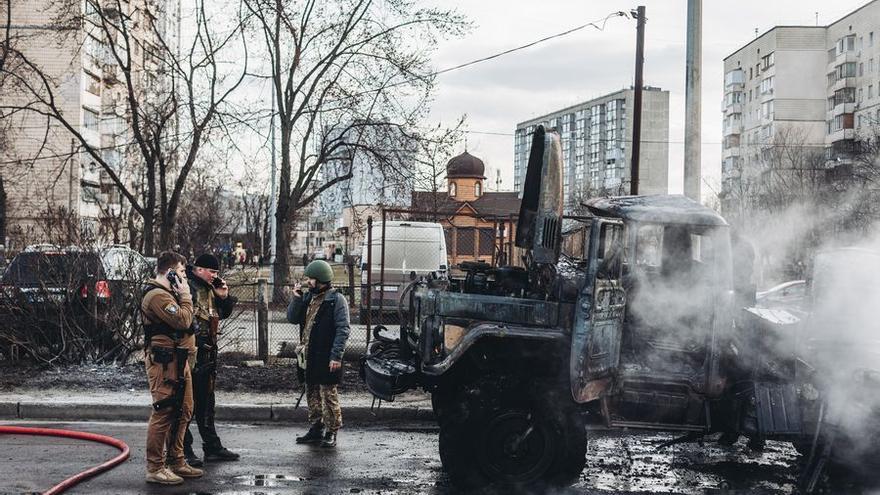 Soldados del ejercito ucraniano observan un vehículo militar calcinado  en Kiev. (Diego Herrera/ Europa Press)