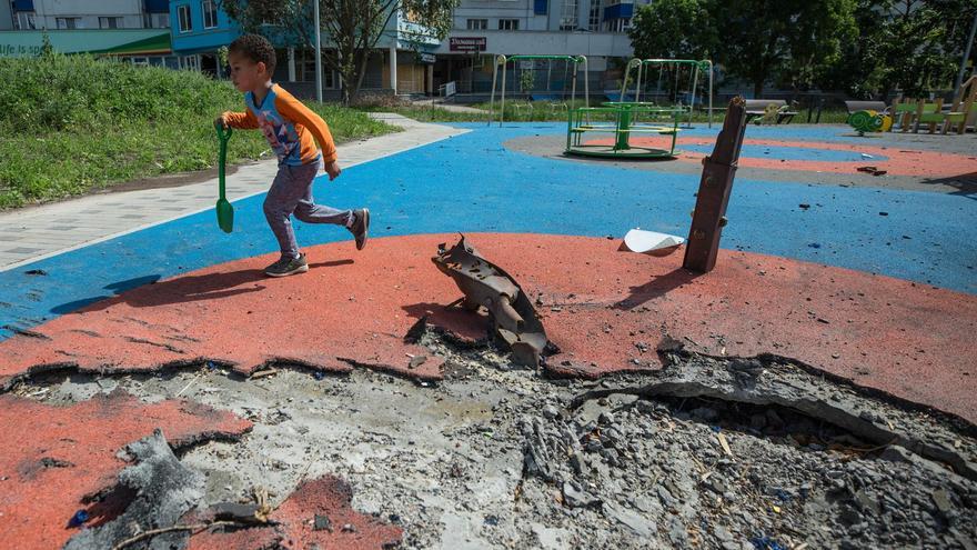 Yuri, un niño de 4 años, juega en un parque infantil junto a un boquete provocado por un bombardeo en Járkov. (EFE)