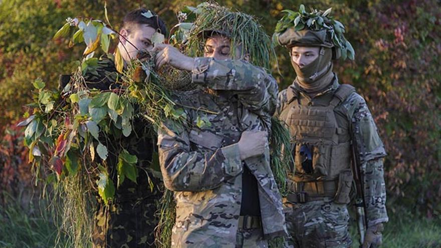 Los civiles ucranianos aprenden a enmascararse durante el entrenamiento para que los civiles adquieran habilidades militares en un campo de tiro en Lviv, Ucrania. (EFE)