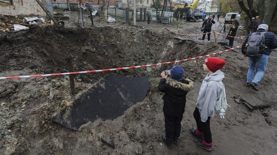 Los lugareños observan el agujero del bombardeo tras un reciente ataque con cohetes en la aldea de Solonka. (EFE/EPA/Mykola Tys) 